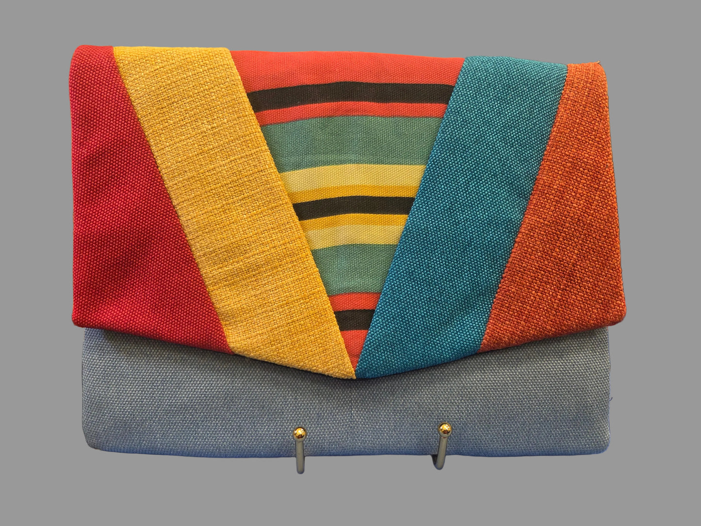 Colorful woven handbag with geometric pattern on a blue surface