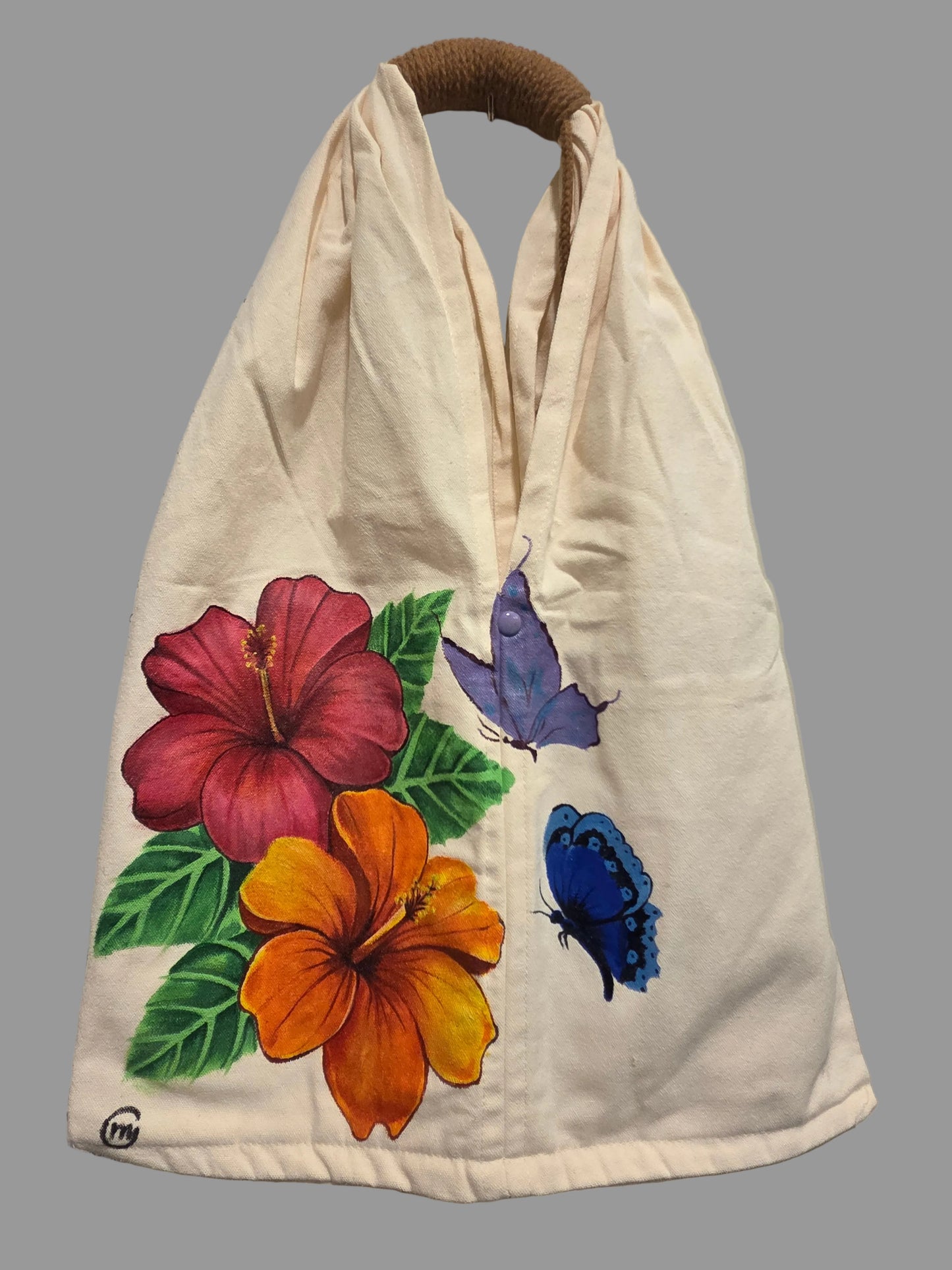 Beige bag with floral and butterfly designs on a surface with papers underneath