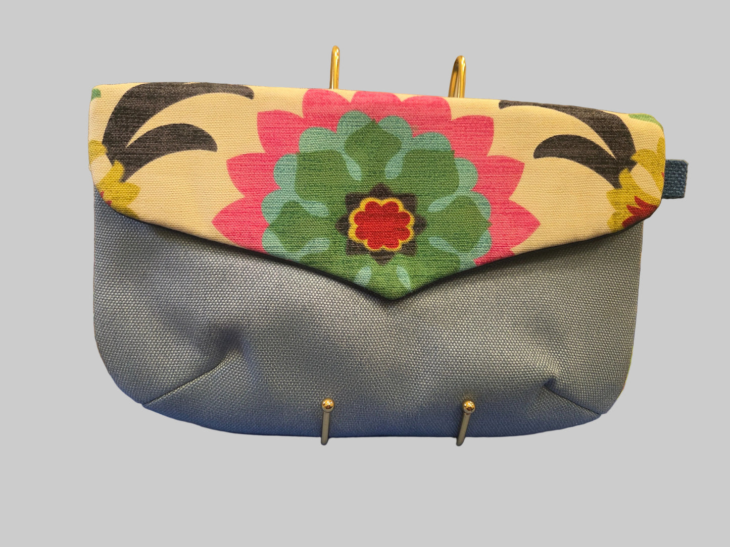 Floral-patterned clutch bag on a blue surface with a blurred background