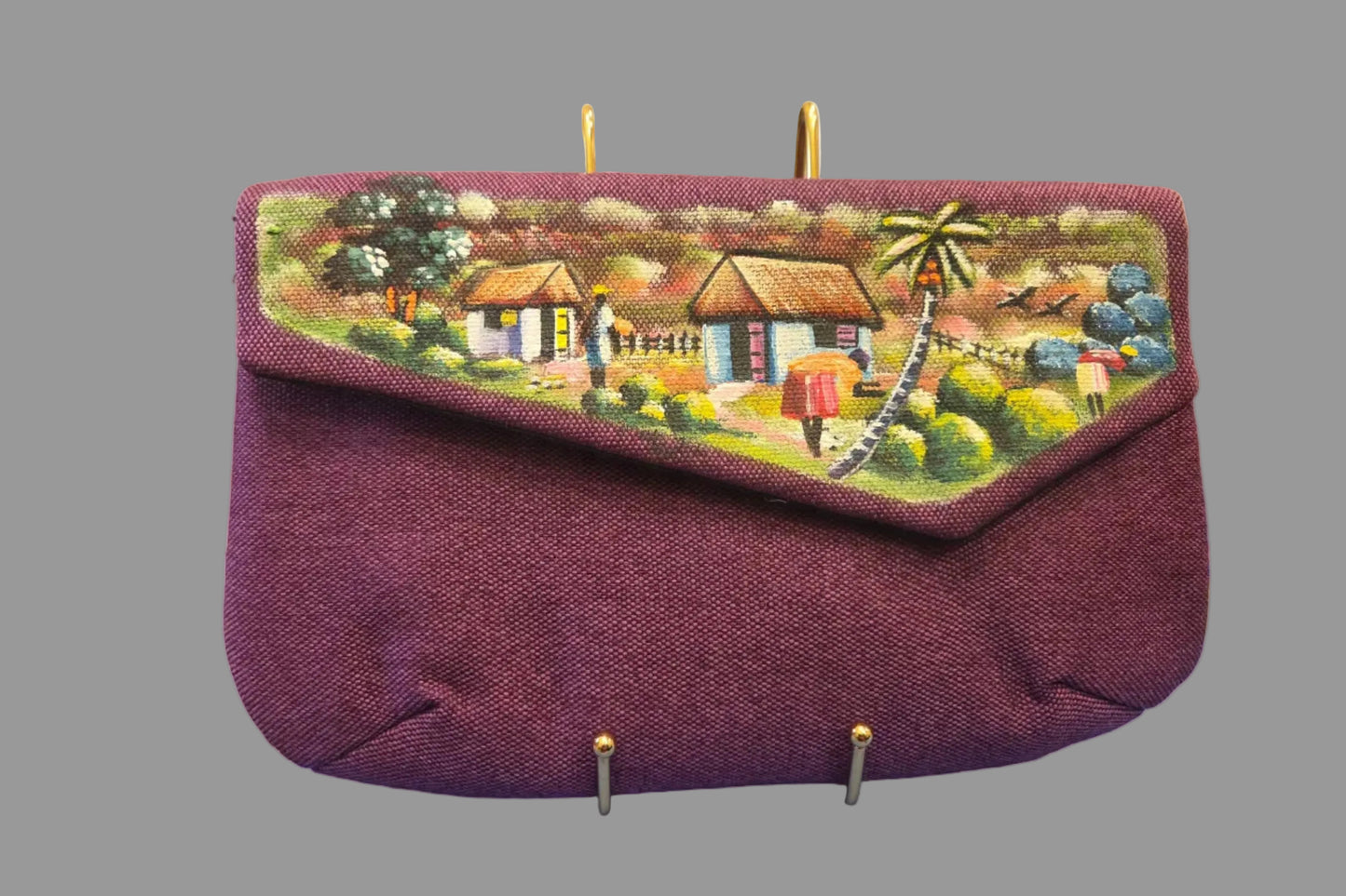 Purple bag with a scenic design on a table with various items in the background